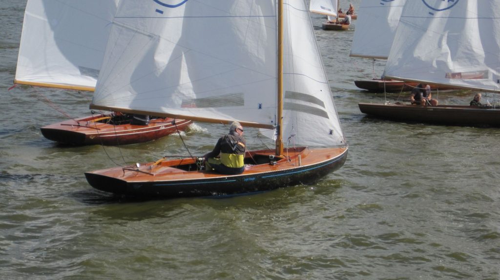 Meerdere houten zeilboten varen dicht bij elkaar