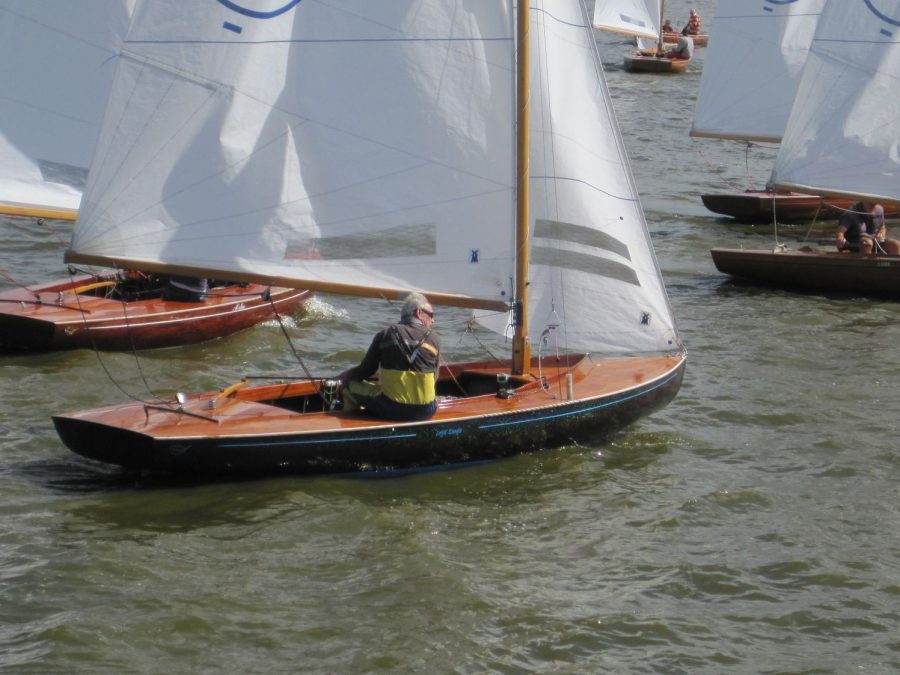 Meerdere houten zeilboten varen dicht bij elkaar