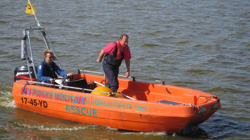 Oranje begeleidingsboot met vrijwilligers op het meer