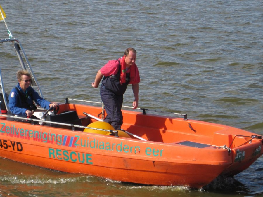 Oranje begeleidingsboot met vrijwilligers op het meer