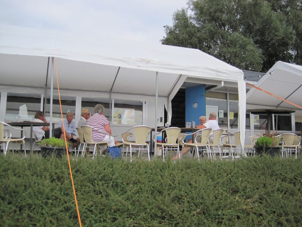 Mensen zitten op het terras onder een tent