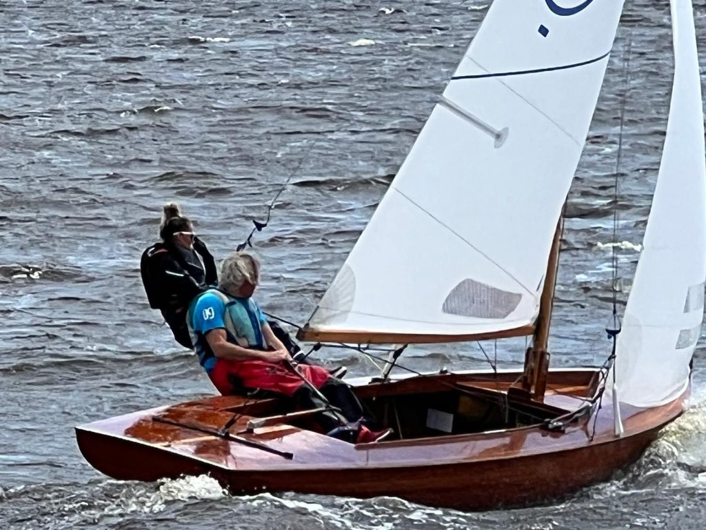 Zeilers in een houten jol bij harde wind