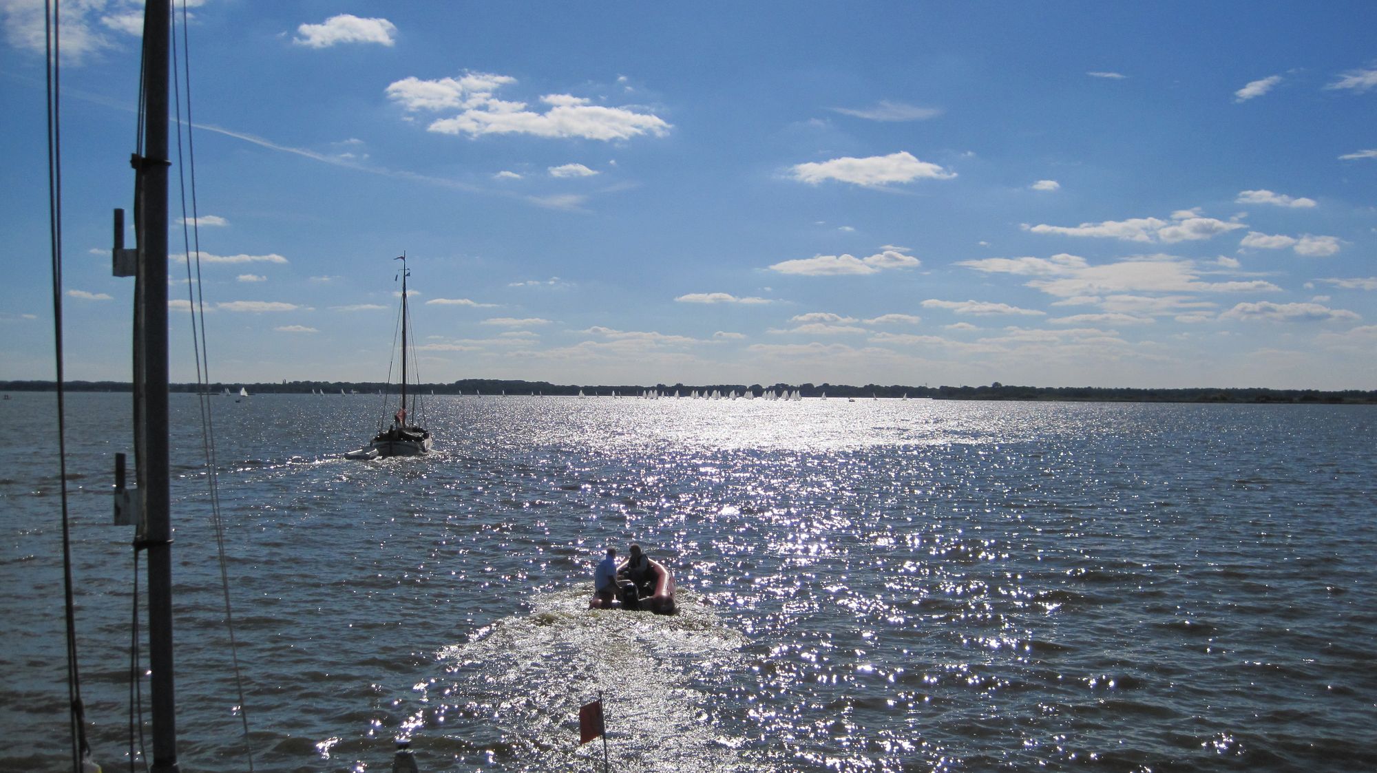 Zonlicht glinstert op het meer, op de achtergrond een zeilboot