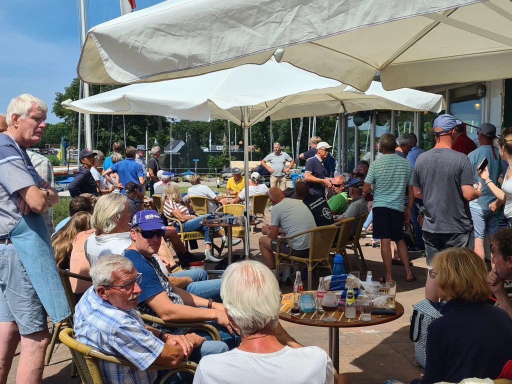 Veel mensen op een terras onder parasols