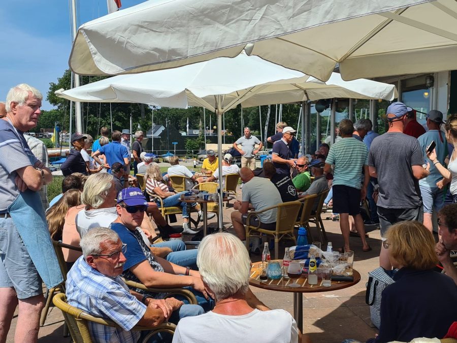 Veel mensen op een terras onder parasols