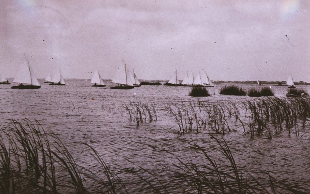 Oude foto van zeilboten achter het riet op het meer