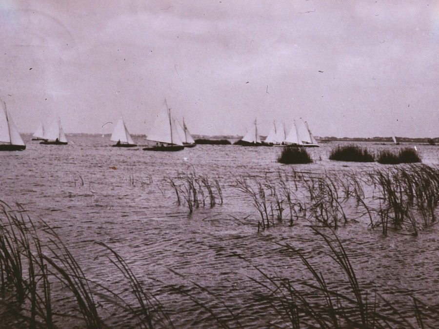 Oude foto van zeilboten achter het riet op het meer